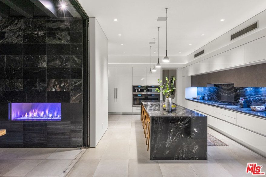 The kitchen island and oversized fireplace are visible.