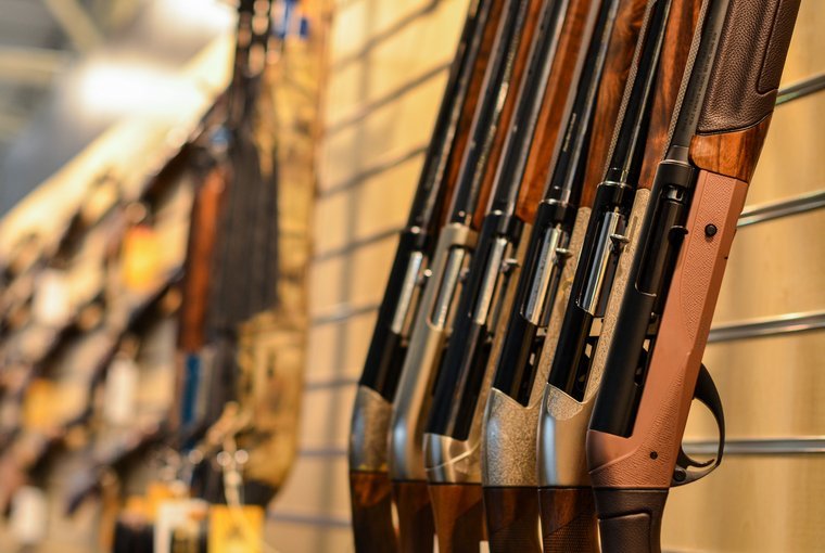 Series of semi-automatic shotguns leaning against a wall in a retail setting.